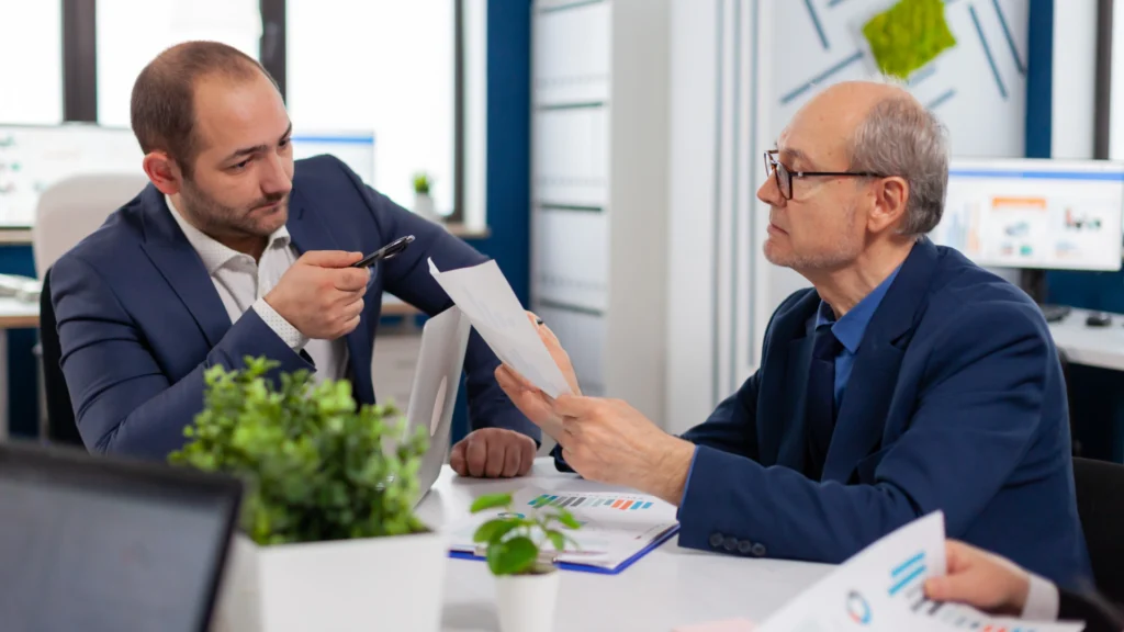 two men in business suits discussing documents during a meeting