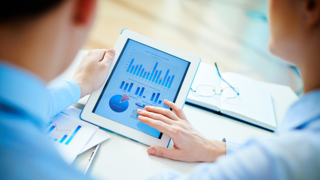 two people analyzing charts and data on a tablet