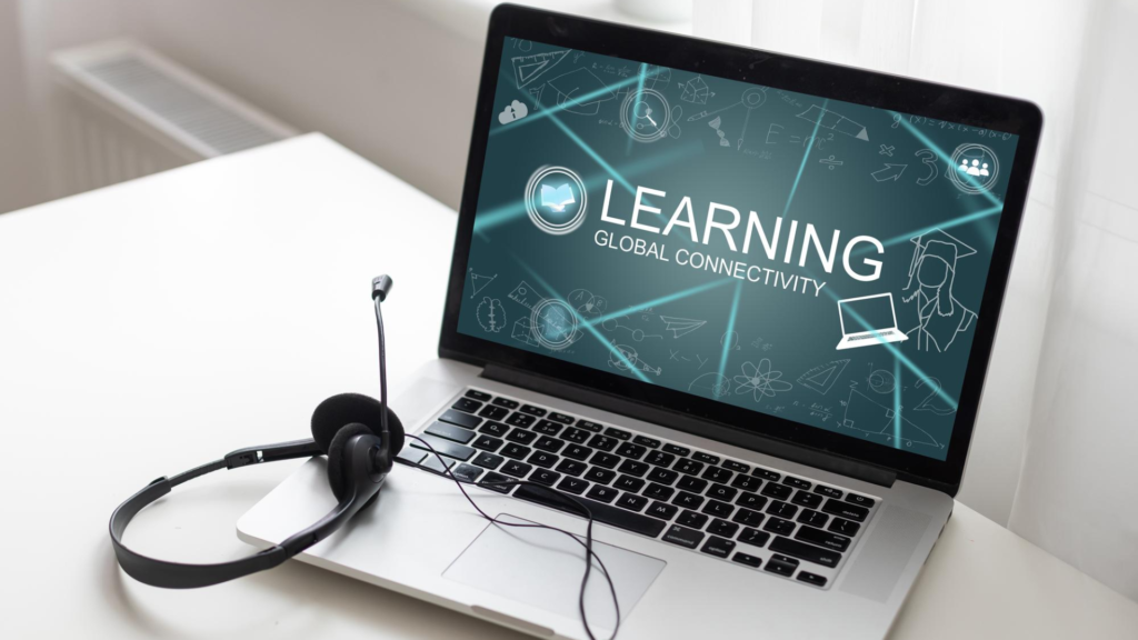 laptop displaying the text “Learning Global Connectivity” with a headset and microphone beside it